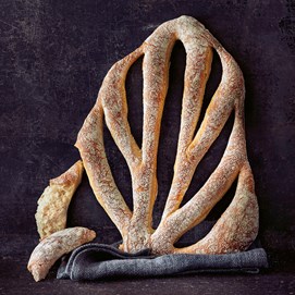 Buchcover „Die neue Brotbackformel“ von Lutz Geißler mit gelbem Hintergrund und Brotauswahl im Arm.