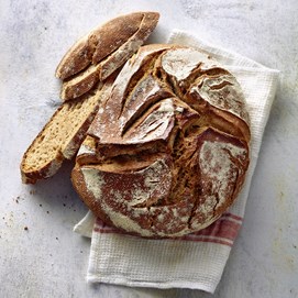 Buchcover „Brot backen in Perfektion mit Sauerteig“ mit Brotfotos, Gebäck und Porträt von Lutz Geißler.