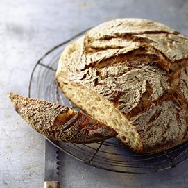 Buchcover „Brot backen in Perfektion mit Sauerteig“ mit Brotfotos, Gebäck und Porträt von Lutz Geißler.