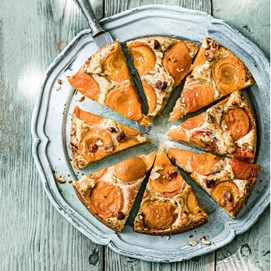 Buchcover „Deftig vegan mediterran“ mit goldbrauner Gemüsequiche, dekoriert mit Tomaten, Oliven und Kräutern.