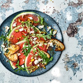 Buchcover „Deftig vegan mediterran“ mit goldbrauner Gemüsequiche, dekoriert mit Tomaten, Oliven und Kräutern.