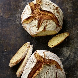 Buchcover „Brot backen in Perfektion“ von Lutz Geißler mit fünf Brotaufnahmen auf beigefarbenem Hintergrund.