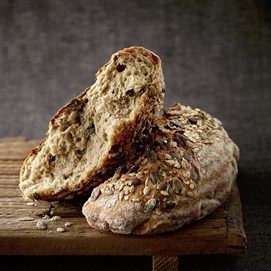 Buchcover „Brot backen in Perfektion“ von Lutz Geißler mit fünf Brotaufnahmen auf beigefarbenem Hintergrund.