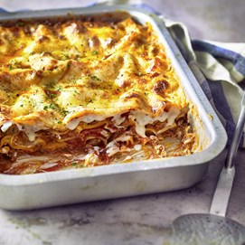 Buchcover „Come a casa“ mit Serena Loddo beim Kochen in heller Küche, Lasagneform im Vordergrund.