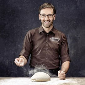 Buchcover „Brot backen in Perfektion“ von Lutz Geißler mit fünf Brotaufnahmen auf beigefarbenem Hintergrund.