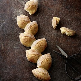 Buchcover „Brot backen in Perfektion“ von Lutz Geißler mit fünf Brotaufnahmen auf beigefarbenem Hintergrund.