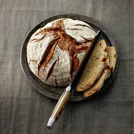Buchcover „Brot backen in Perfektion“ von Lutz Geißler mit fünf Brotaufnahmen auf beigefarbenem Hintergrund.